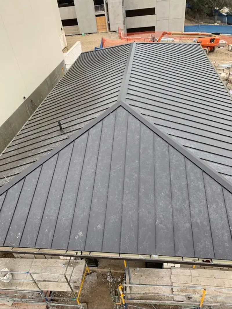 Commercial metal roof construction with crane equipment in Ash